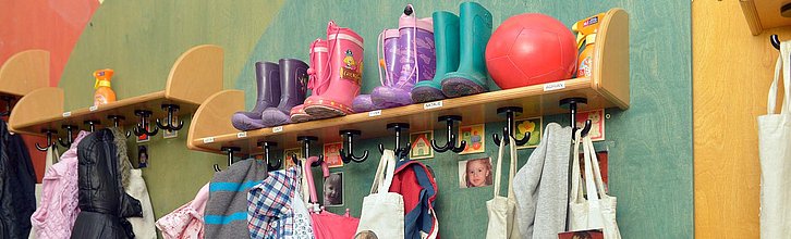 Garderobe in einer Kita mit Jacken, Gummistiefeln und Bildern